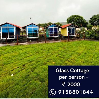 Small glass cottages with red roofs on lush green grass under a cloudy sky.