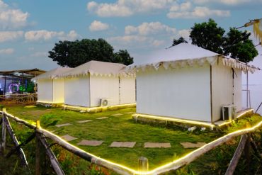 White tents set up on a grassy area under a blue sky with some clouds.