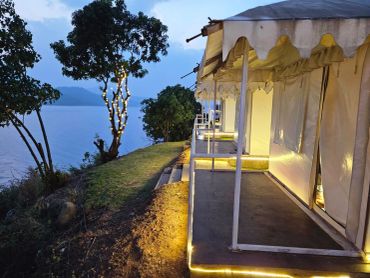 Cozy lakeside tent with warm lights at dusk.