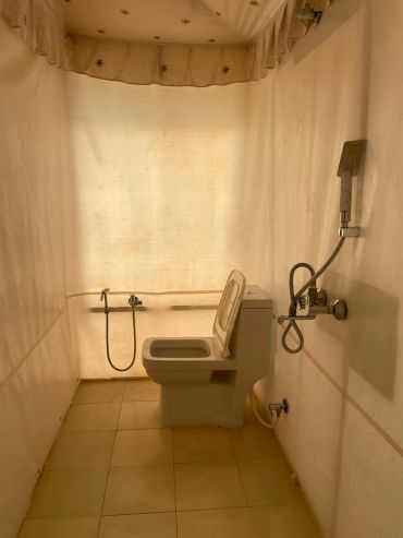 Minimalist bathroom with a toilet and shower area separated by a curtain.