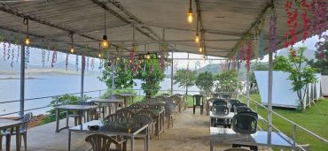 Outdoor lakeside dining area with hanging lights and floral decorations.