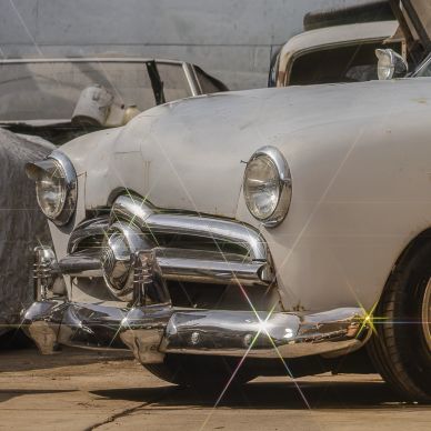 Parte frontal de un automóvil clásico blanco con detalles cromados.