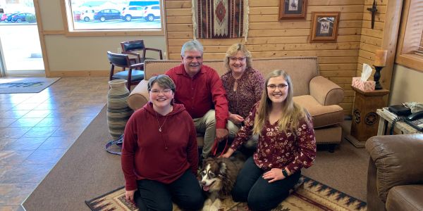 Family of four with a dog in a cozy living room.