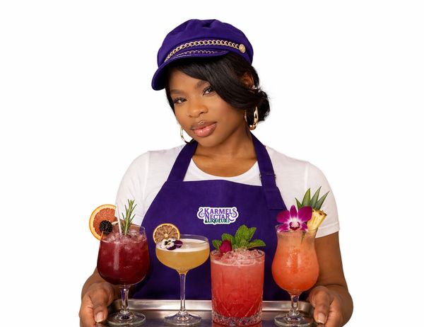 Woman holding a tray with colorful cocktails wearing purple apron and cap.