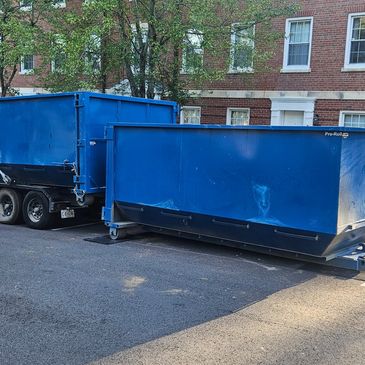 Blue waste containers outside a brick building.