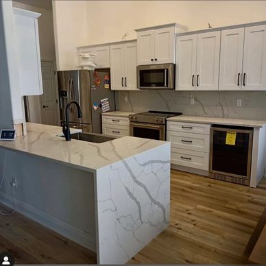 "White cabinets and quartz countertops with sleek black hardware create a clean, modern kitchen"