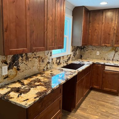 "Rich wood cabinets paired with striking granite countertops and backsplash create a warm, natural, and elegant kitchen."