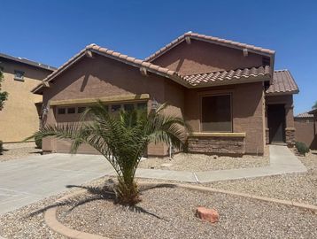 Single-story house with brown stucco exterior and desert landscaping.