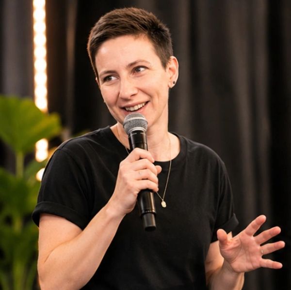 Person speaking confidently into a microphone with a smile.