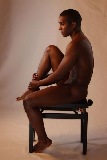 nude man in profile sitting on a chair