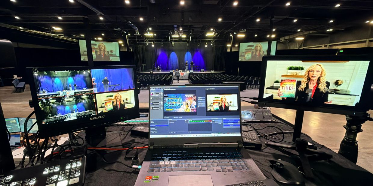 Professional multi-camera livestream production setup with video switching equipment and monitors at a large conference venue.