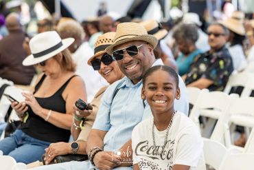 Three generations smiling at an outdoor event.