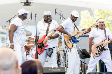 Four men performing on stage with guitars and drums.