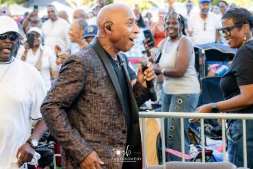 Man singing to a crowd at an outdoor event.