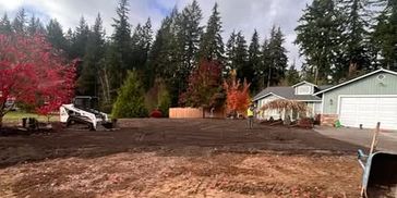 Excavation in residential yard heavy machinery leveling and shaping soil for a landscape project.