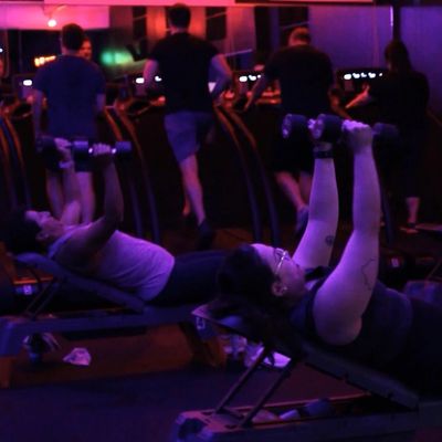 People working out in a dimly lit gym.