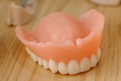Full upper denture placed on wooden surface.