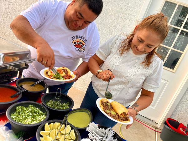 Smiling clients serving themselves at a taco self service bar party event.