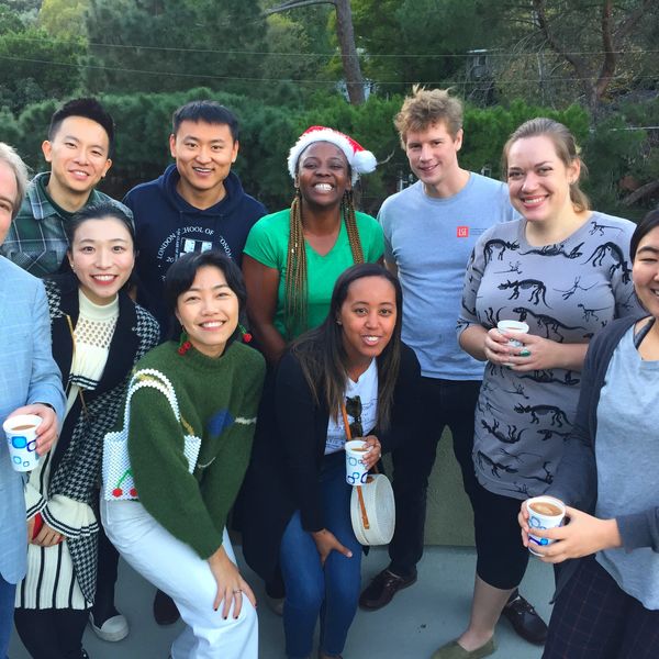 A diverse group of friends smiling and holding coffee cups outdoors.