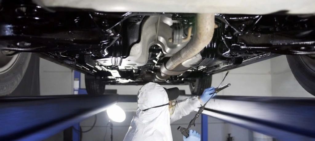 shows a man spraying rust proofing coating