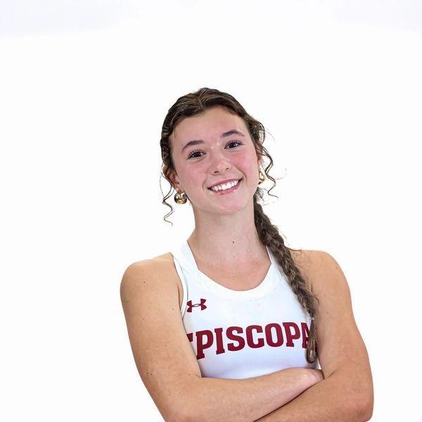 Smiling young athlete in a white Episcopal sports tank top with arms crossed.
