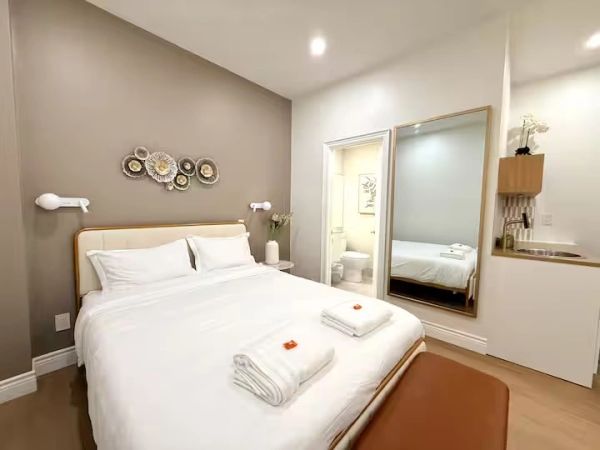 Cozy modern bedroom with white bedding and decorative wall art.