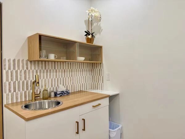 Modern kitchenette with wooden countertop and geometric tile backsplash.