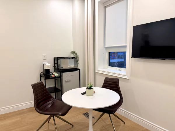 Small dining area with two chairs, round table, and mounted TV.