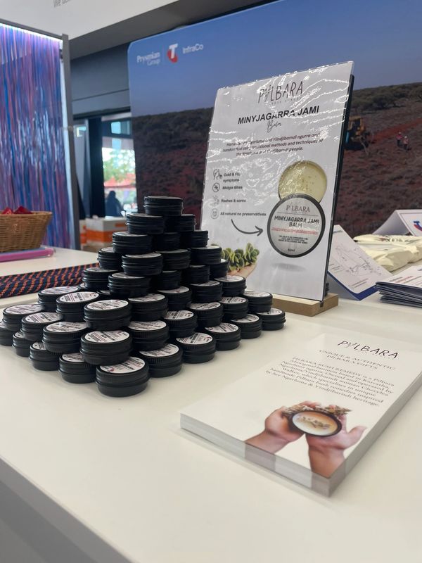 Stacked jars of Pilbara Minyagarrja Jami balm displayed on a table with informational brochures.