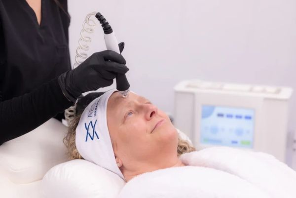 Woman receiving a facial treatment with a handheld device in a spa.