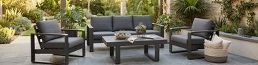 Modern outdoor seating with gray cushions in a lush garden patio.