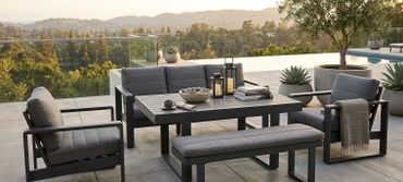Modern outdoor patio set with gray cushions and scenic mountain view.