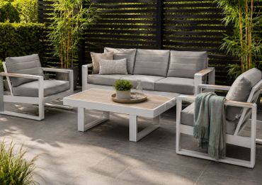 Modern outdoor patio set with gray cushions and a wooden coffee table on tiled floor.