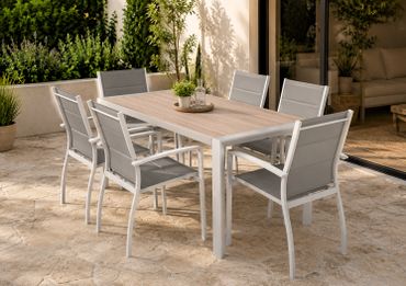 Modern outdoor dining set with six chairs on a stone patio.