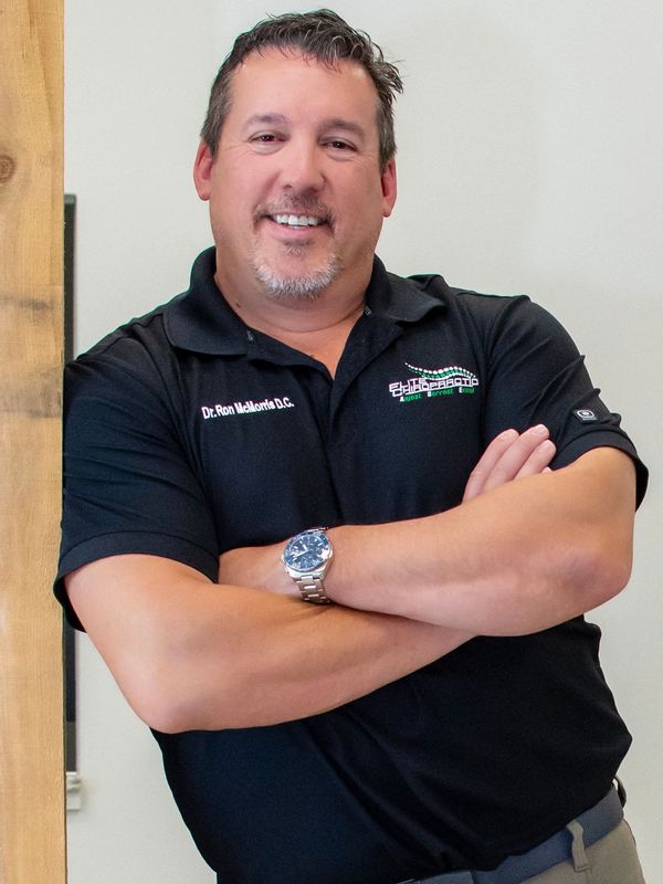 Man smiling with arms crossed wearing a black shirt.