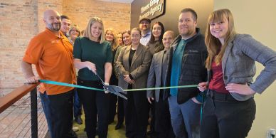 Group of people celebrating a ribbon-cutting event indoors.