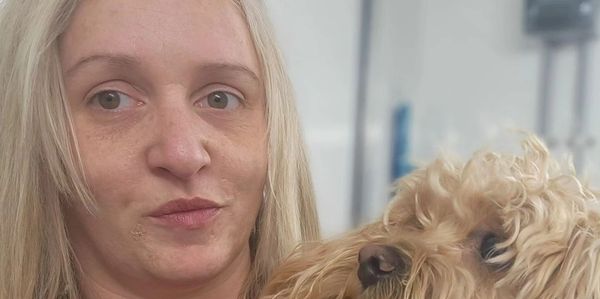 A woman holding a fluffy dog