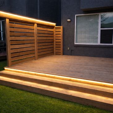 Wooden deck with built-in warm lighting on steps and railing.