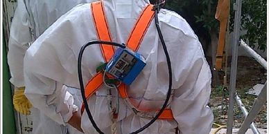 Person in protective suit with equipment strapped on back.