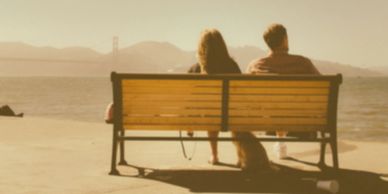 Couple sitting on a bench looking over the water