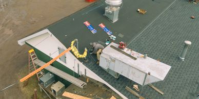 Worker repairing a rooftop with tools and materials spread around.
