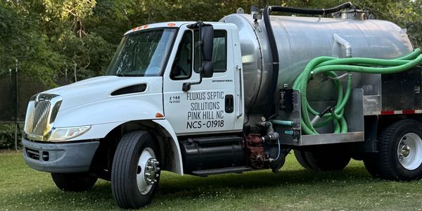 Septic service truck parked on grass.