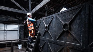 Worker in safety gear inspecting industrial machinery inside a factory.