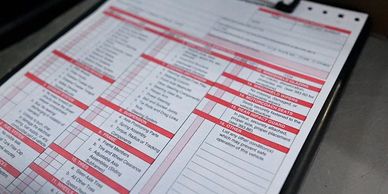 A close-up of a checklist or form with red headers on a clipboard.