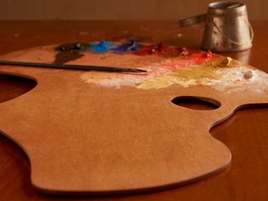 Wooden artist palette with colorful paint blobs and a brush.