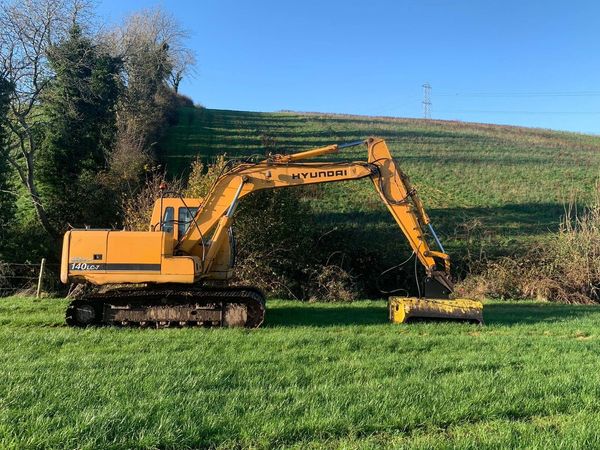 Yellow Hyundai excavator on green grass field.