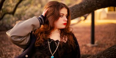 Young woman with red hair posing outdoors.