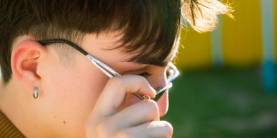 Person adjusting glasses outdoors.