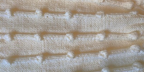 Textured white knitted fabric with raised bumps.