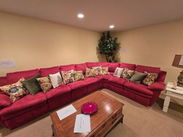 Red sectional sofa with floral cushions in cozy living room.
